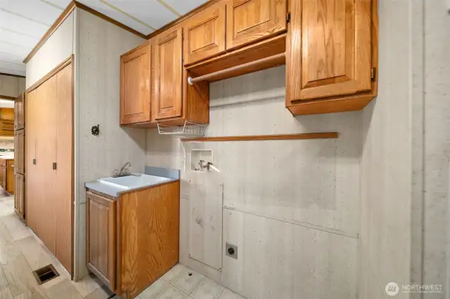 Laundry area in utility room with utility sink and lots of cabinets.