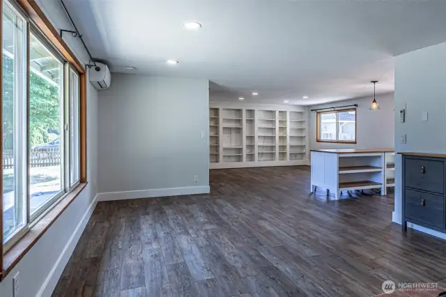 From the front entry into the living room. Open concept into the dining/family rooms - LVP flooring and built in bookshelves.