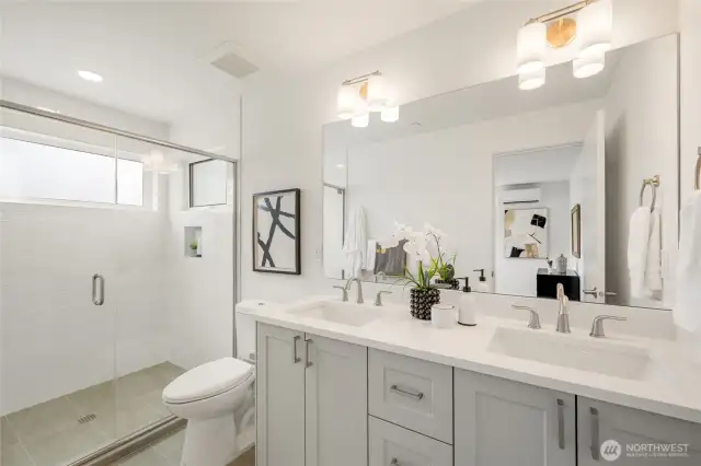 Walk-in tile shower and double sinks.