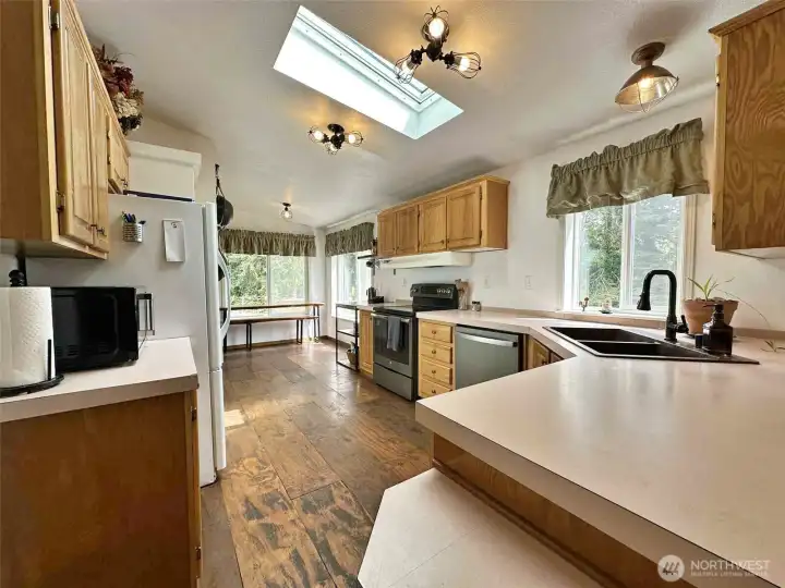 Kitchen with eating space, coffee nook, airy atmosphere, and abundant daylight from numerous windows."