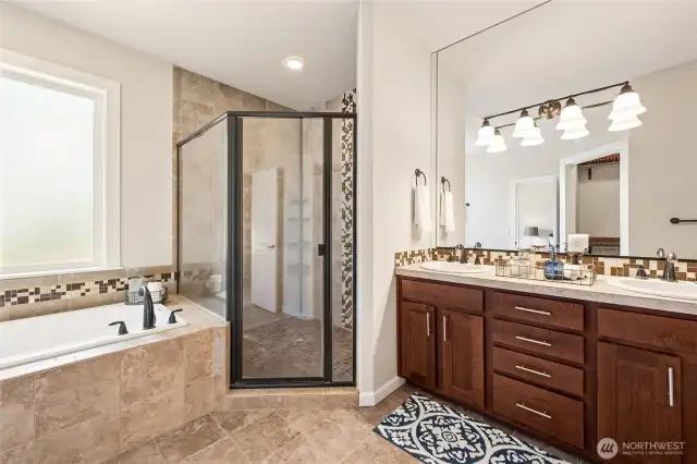 Spa-inspired ensuite with soaking tub, fully tiled shower, and double vanity.
