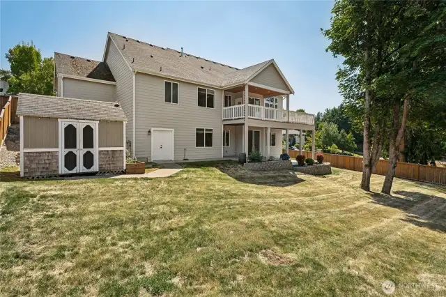 Large fenced backyard with a coordinating storage shed and a sprawling lawn for endless outdoor enjoyment.