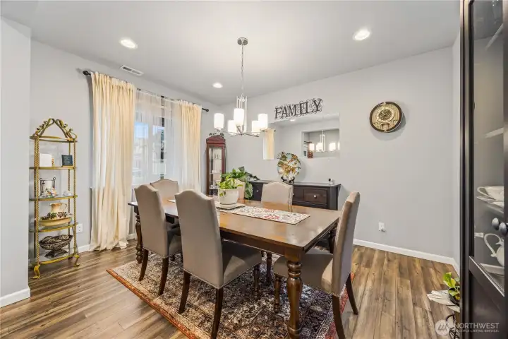 Formal dining room with soft natural light, and modern chandelier