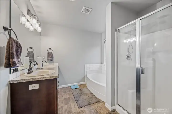 Primary ensuite featuring a dual-sink vanity, soaking tub, and separate glass-enclosed shower. Includes a private water closet and spacious walk-in closet for added comfort and convenience.