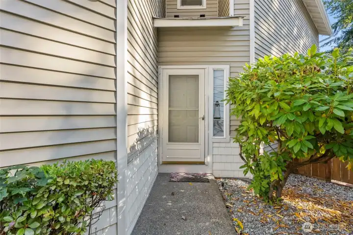 Tucked away entry with shrub lined walkway to front door. Rhododendron shrub next to front door provides beautiful color when in bloom during the Spring.