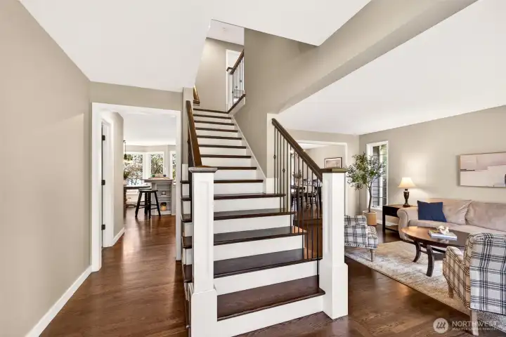 The open entry foyer with its striking staircase — featuring dark hardwood treads and iron balusters — creates an immediate sense of architectural character, with views flowing naturally toward the living and dining areas.