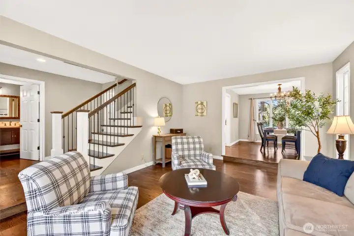 The generously sized living room offers a relaxed, connected flow between the entry, dining room, and main level powder room — a versatile space designed for how people actually live.