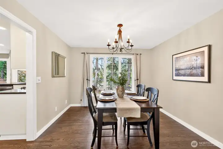 The formal dining room is perfectly scaled for gatherings, with garden views through a large picture window and an elegant chandelier overhead — a room that makes every meal feel like an occasion.