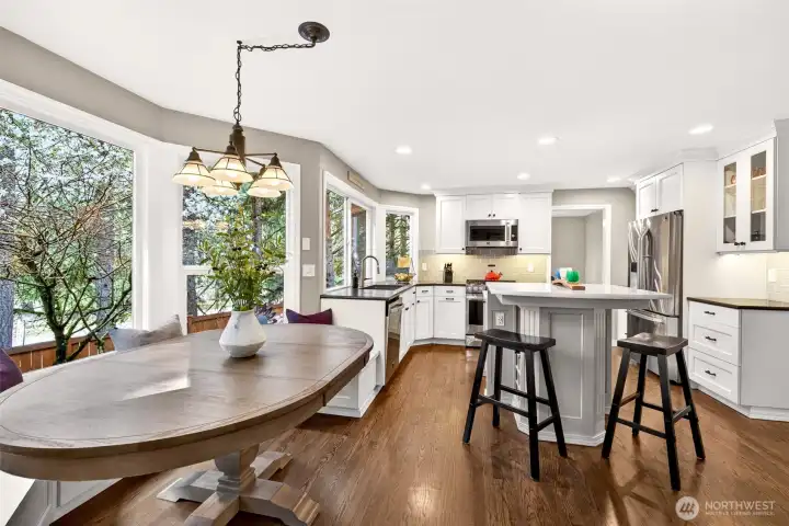 The kitchen's open layout flows effortlessly from the nook to the island and beyond — a thoughtfully designed space where natural light, treetop views, and easy indoor-outdoor access to the deck make every day feel elevated.