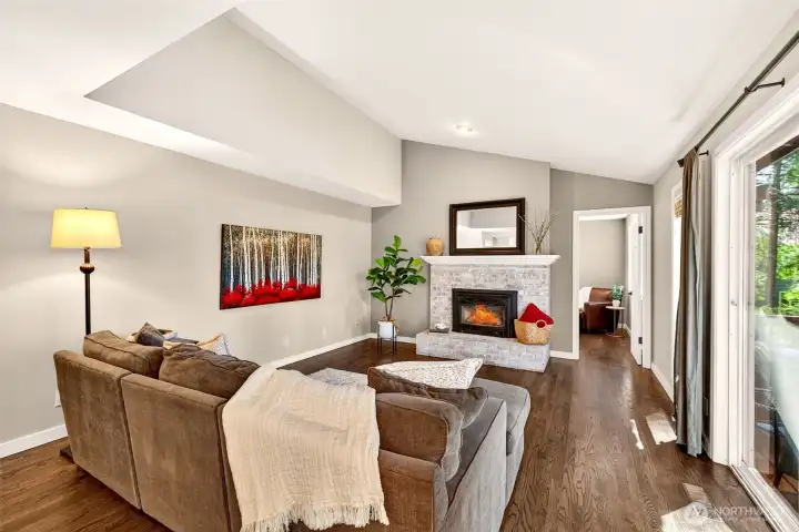 The vaulted family room is anchored by a classic brick fireplace and opens directly to the back deck — a naturally bright, airy gathering space that transitions effortlessly between cozy evenings in and outdoor entertaining.