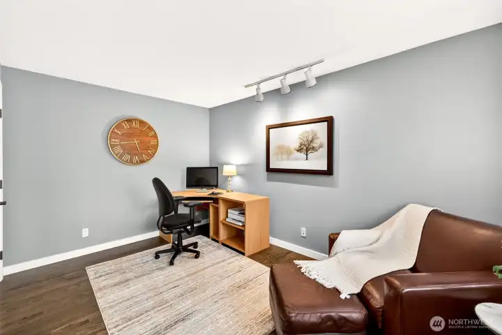 A versatile main-level room with track lighting and hardwood floors offers an ideal setup for a home office, den, or flex space — a valuable feature for today's remote and hybrid work lifestyle.