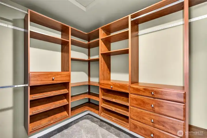 The primary suite's walk-in closet delivers a boutique-level storage experience — with rich wood built-ins, adjustable shelving, pull-out shoe racks, and generous drawer space thoughtfully designed for two.