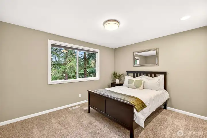 A secondary bedroom with plush carpet, a treetop window view, and a tranquil, private feel — ideal as a guest room, second bedroom, or a quiet upstairs retreat.
