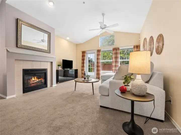 The living room is warm and inviting, with vaulted ceilings and large windows that bring in great natural light and views of the greenery outside. The cozy gas fireplace adds a nice focal point, while the open layout makes it an easy space to relax or entertain.