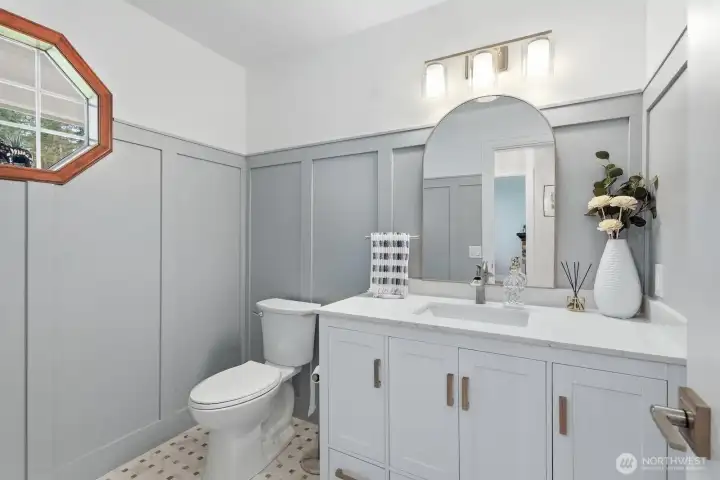 Updated guest 1/2 bath with board and batten wainscoting and designer tiled floor.