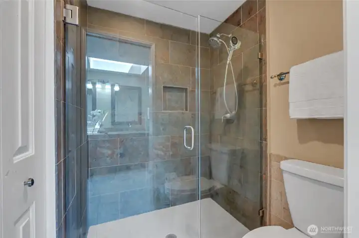 Shower and toilet in primary ensuite bath with spacious linen closet.