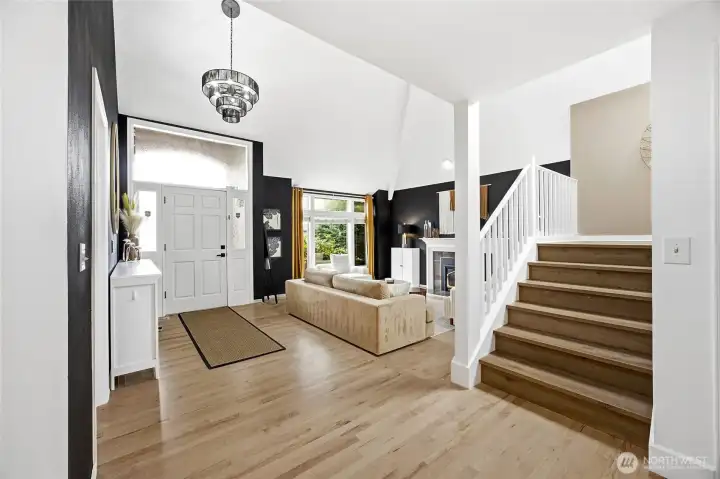 Step through the front door into a grand, light-filled entry showcasing soaring vaulted ceilings and premium wide-plank hard-surface flooring. Crisp white risers and updated modern millwork set an immediate upscale, designer tone