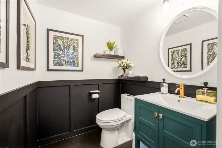 Fully updated main-level powder room featuring a contemporary vanity, modern matte-black hardware accents, and elegant classic wainscoting trim details.