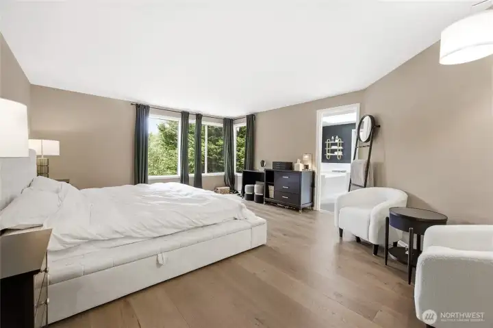 Alternative view of the primary bedroom showcasing the impressive room dimensions, continuous wide-plank flooring, and versatile space for a seating area or secondary wardrobe