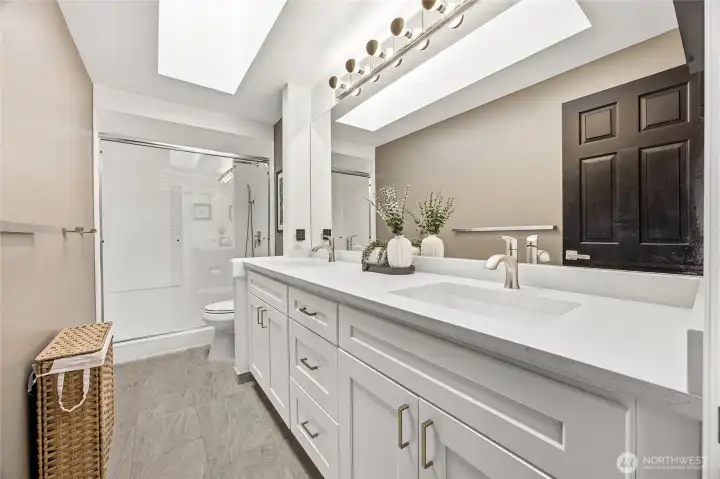 Fully renovated full hall bathroom servicing the secondary bedrooms, beautifully finished with a modern white vanity, updated plumbing fixtures, an oversized mirror, and crisp contemporary design accents.