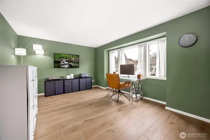 Third bright upper-level bedroom highlighting the home's continuous carpet-free footprint, neutral designer paint tones, and generous natural light pouring in from the wide window line.