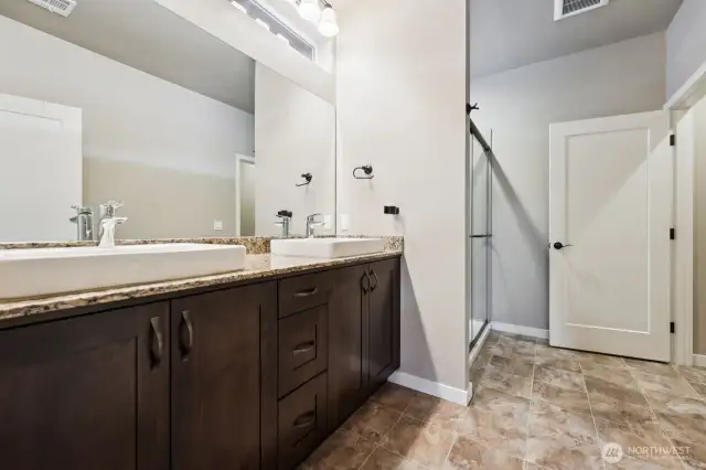 Beautiful ensuite primary bath with vessel sinks and tile step-in shower