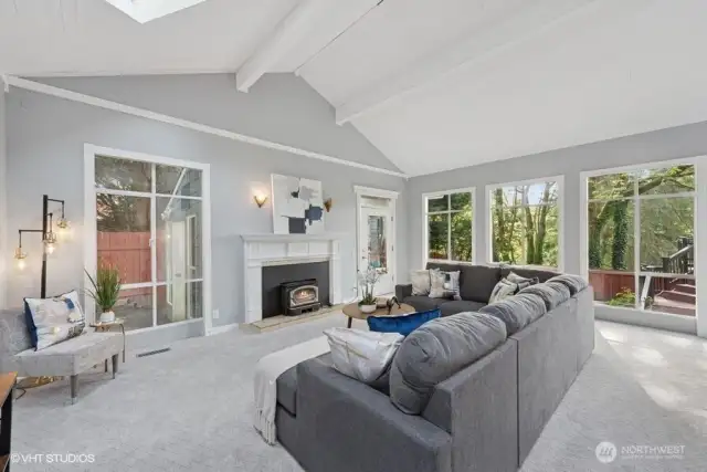 Living Room with vaulted ceilings, fireplace, and door to green house.