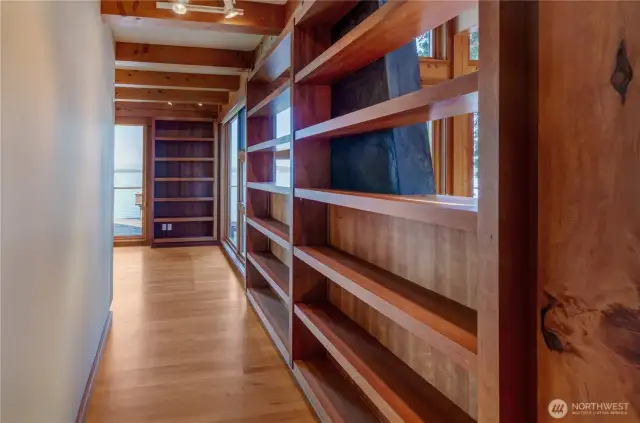 Short hallway off great room to library is lined with custom shelving
