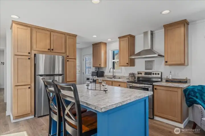 Kitchen w/ island and stainless steel appliances and hood.