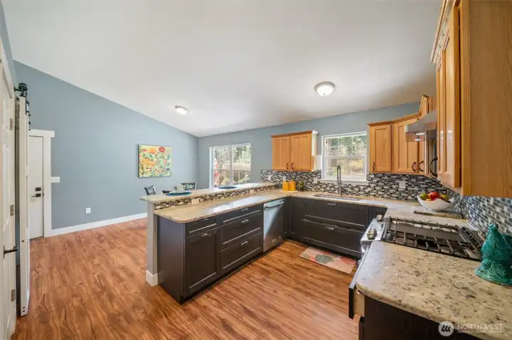 Updated kitchen with granite countertops, tile backsplash, stainless appliances, and abundant cabinetry