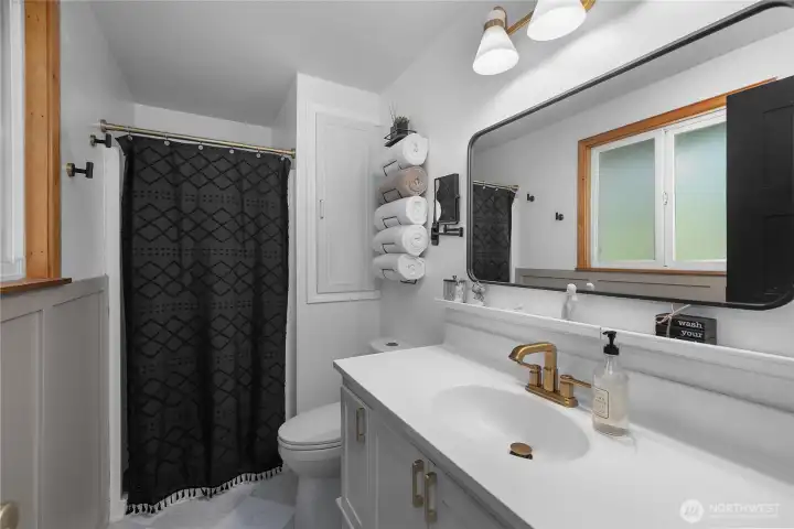 Beautifully updated primary bath with new flooring, fixtures, lighting, and millwork.