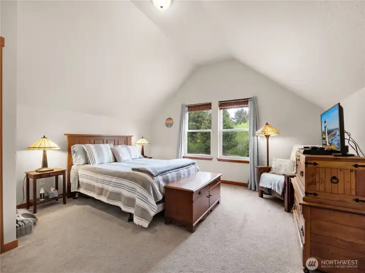 Spacious bedroom with vaulted ceilings, natural light, and peaceful property views.