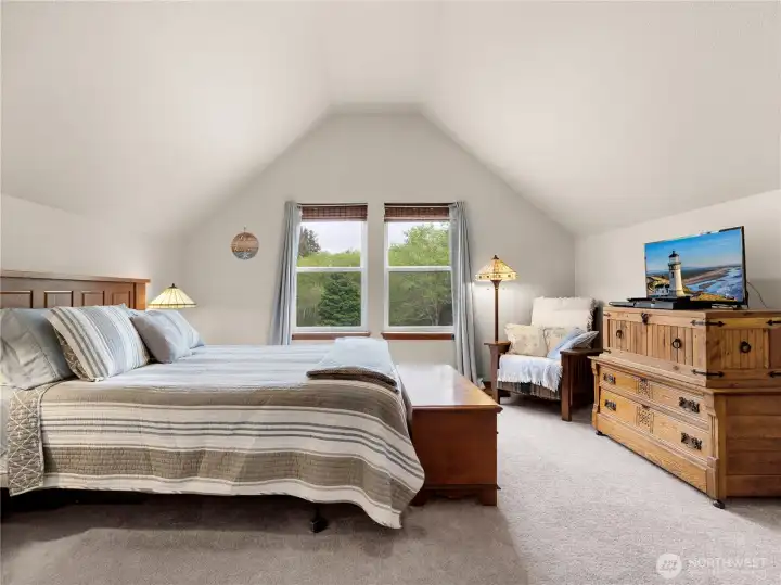 Spacious primary bedroom with vaulted ceilings, soft natural light, and peaceful views of the surrounding property.