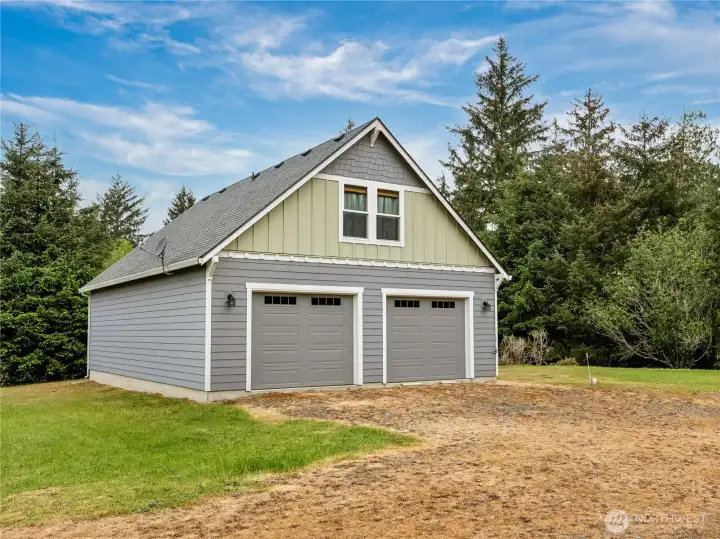 Exterior view showcasing the home built over an oversized garage, additional parking space, and open yard area.