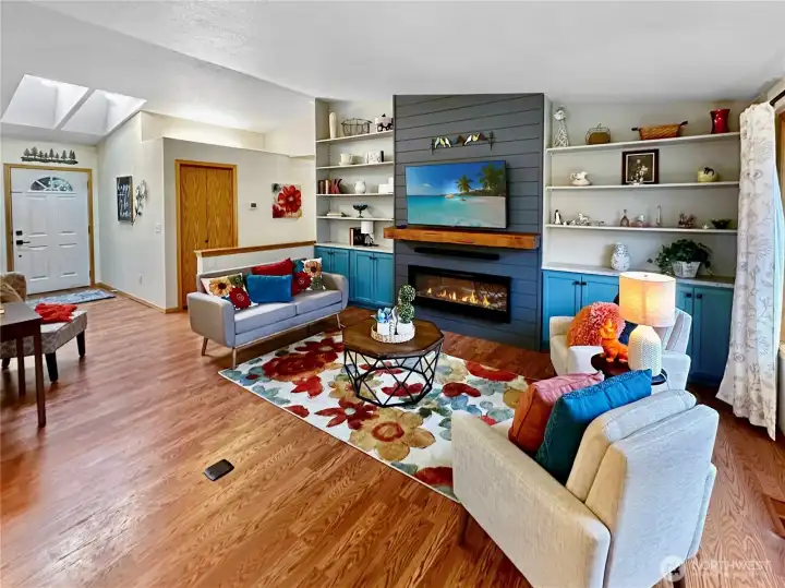 The living room featured vaulted ceiling, laminate floor, electric fireplace with wood mantel which is flanked by display shelves and storage cabinets. The living room featured vaulted ceiling, laminate floor, electric fireplace with wood mantel which is flanked by display shelves and storage cabinets.