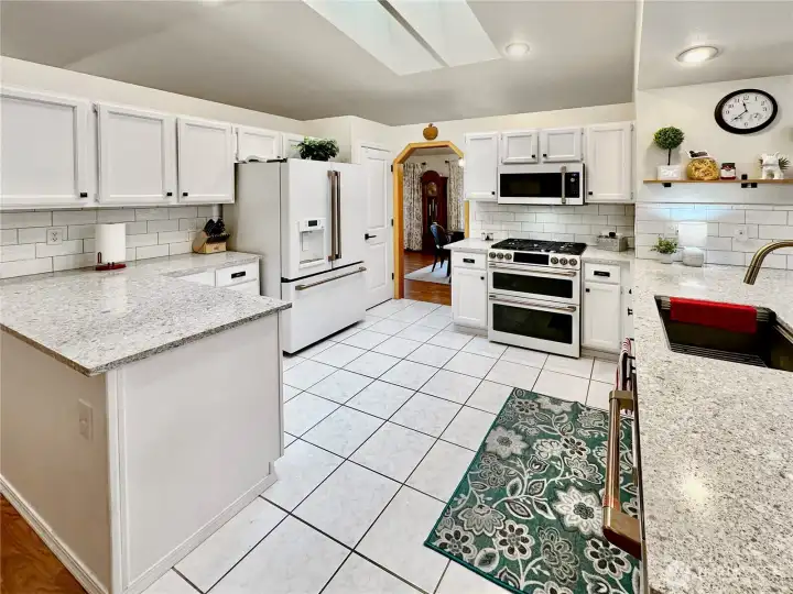 Another view that show the vaulted sky-lighted ceiling and plenty of cabinet space, quartz counters and full tile back-splash. Another view that show the vaulted sky-lighted ceiling and plenty of cabinet space, quartz counters and full tile back-splash.