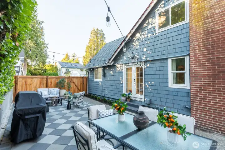 Stylish checkered paver patio with privacy fencing and string lights. Wonderful spot for entertaining or relaxing outdoors.