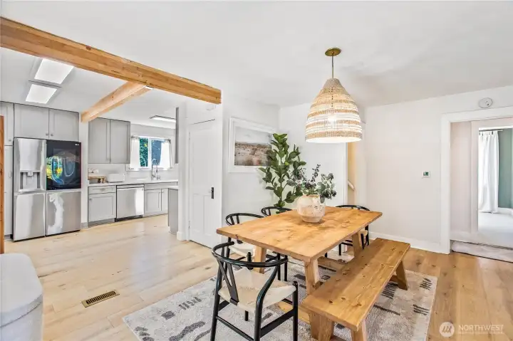 Warm, open dining area framed by wood beams and natural light seamlessly connected to the kitchen and patio