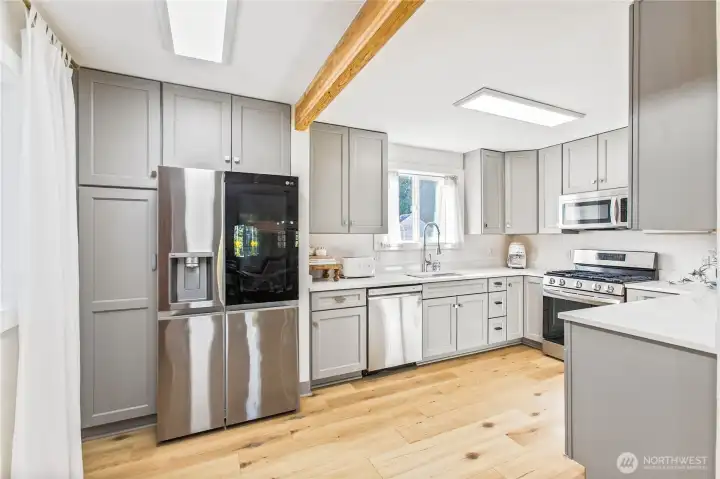 Fully remodeled bright, modern kitchen with Thomasville soft-close shaker cabinetry, updated cabinet hardware, Carrara quartz countertops, LG stainless appliances with dual ice maker, and warm wood accents.