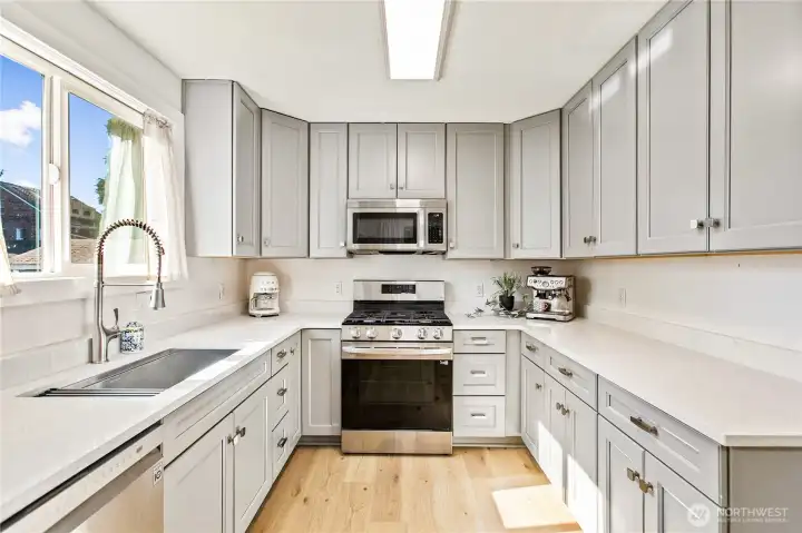 Fully remodeled bright, modern kitchen with Thomasville soft-close shaker cabinetry, updated cabinet hardware, Carrara quartz countertops, LG stainless appliances with dual ice maker, and warm wood accents.