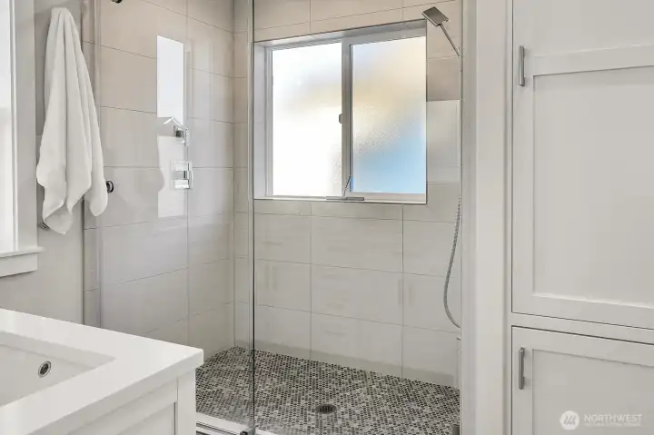 Oversized shower and convenient linen storage complete the room.