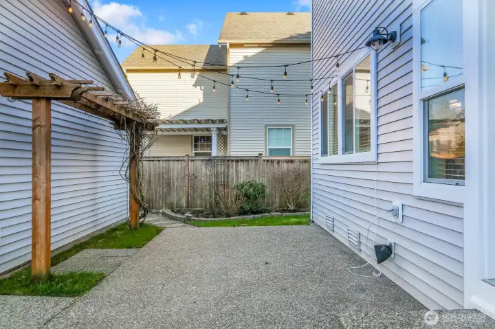 Kitchen door to the right of this photo, leads to this charming patio cafe lights. Imagine the garden in bloom and wisteria vine climbing the trellis. Perfect for relaxing on summer evenings.  Notice the path in the back left of the photo which leads to a convenient side yard with another gate to the driveway.