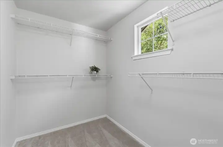 Bright primary closet with natural light from a window.