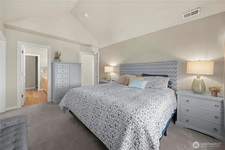 Spa like primary suite with vaulted ceilings and ensuite primary bathroom and shows off the  newer carpet throughout the home.