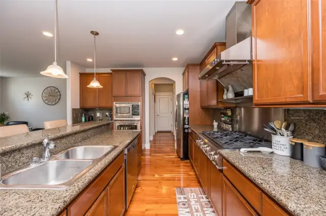 Gorgeous kitchen fully applianced with commercial range hood over gas 6 burner stove, granite counters and plenty of cabinets with upper and lower crown molding