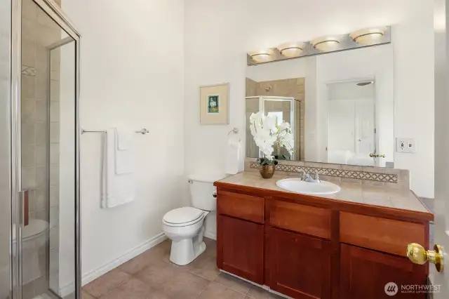 The primary bath has a walk-in shower and jetted tub (to the right of the vanity).