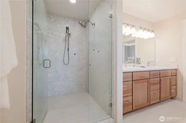 Beautiful quartz surfaces extend into the large shower with Brizo fixtures and window sill.