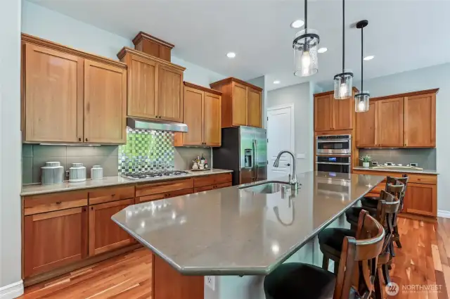 Kitchen with slab granite counters, 42" cherry cabinets with undermount lights, tile and stainless backsplash. The island counter provides plenty of prep space and counter seating.