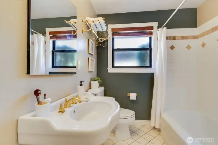 The main floor bath features a pedestal sink, tile floors, and tile shower surround.