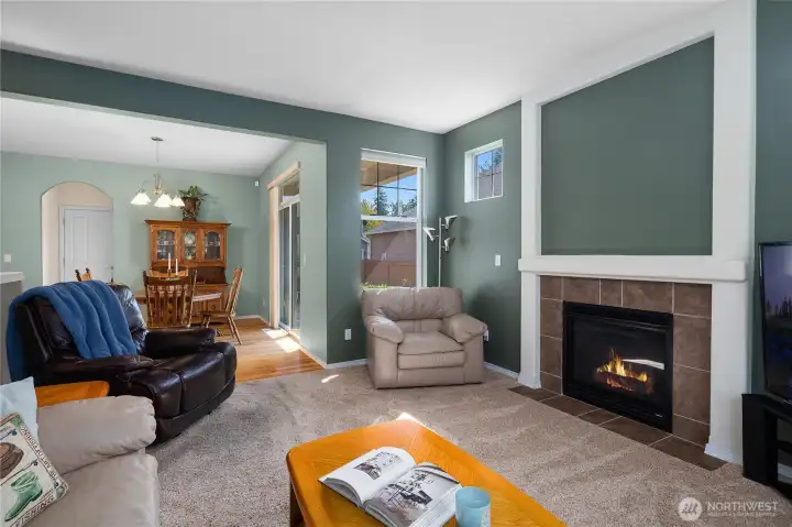 Great room with bright bay windows and gas fireplace leading to dining and kitchen with hardwood floors.